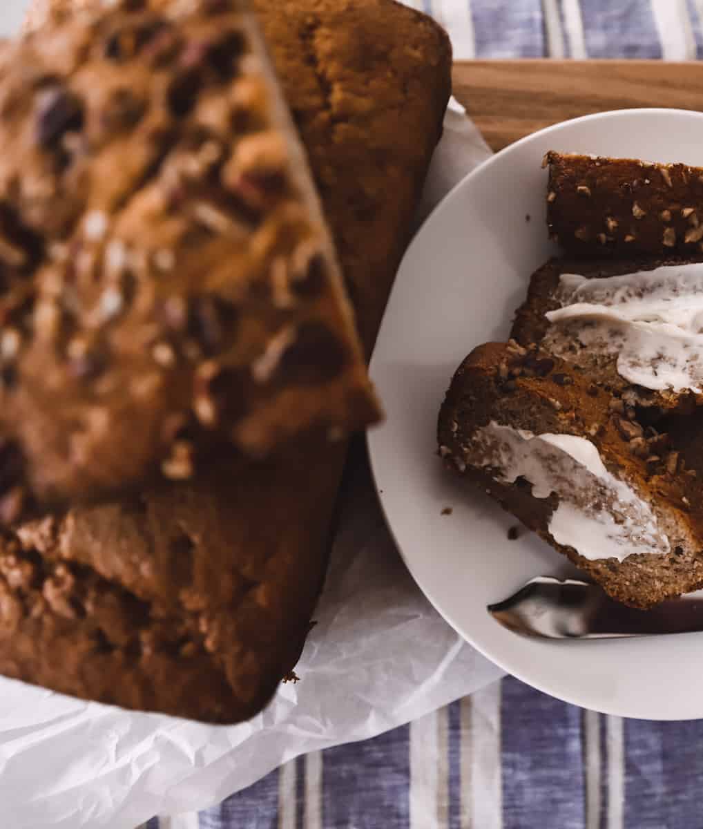 greek yogurt banana bread with nuts on a cutting board with butter