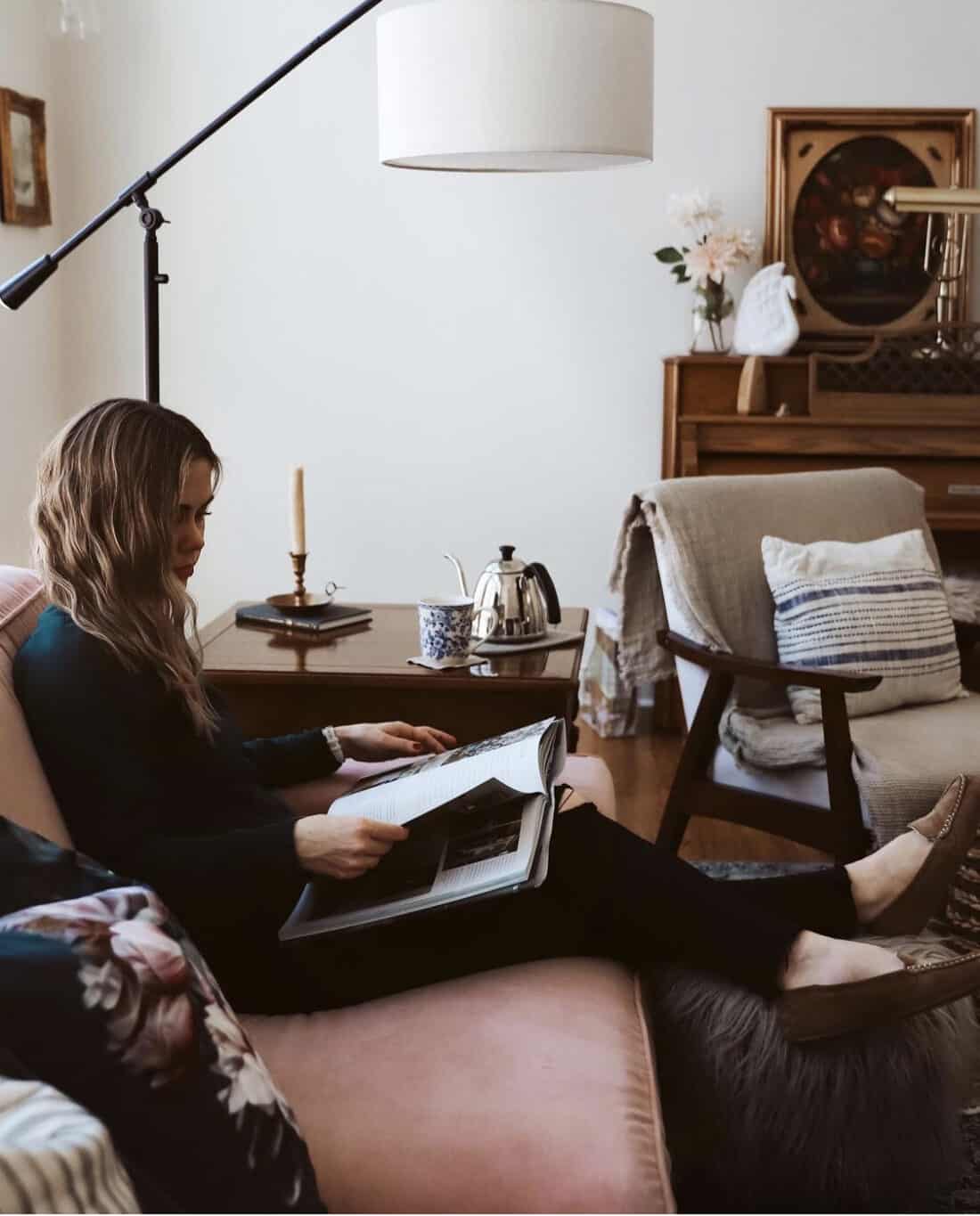 woman sitting on a pink sofa reading