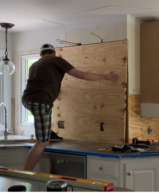 a man adding plywood to a wall