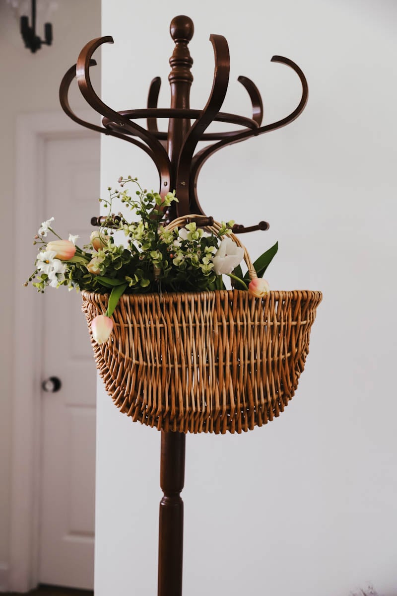 hanging basket on a coat rack with flowers in it