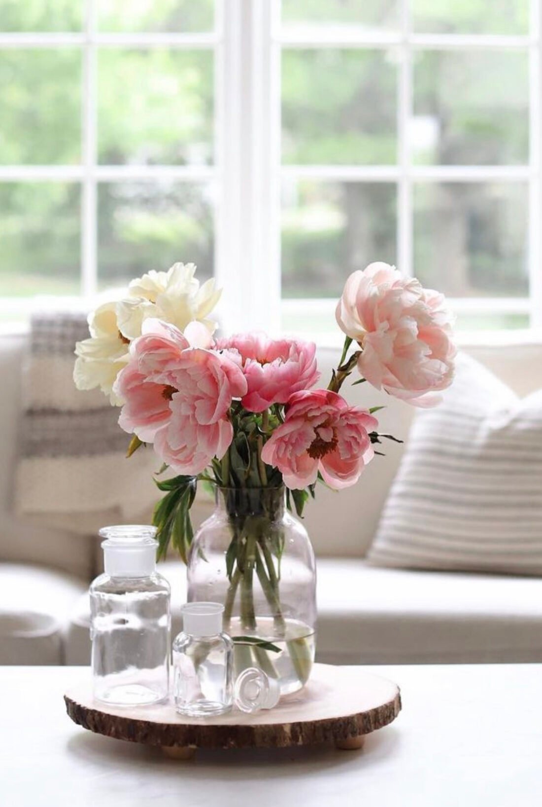 pink and blush peonies in a clear glass vase on a coffee table