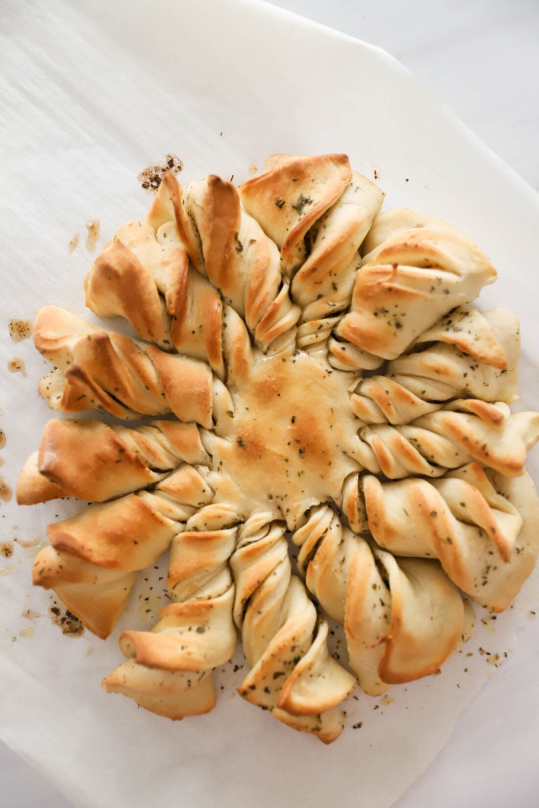 A garlic bread wreath on parchment paper.