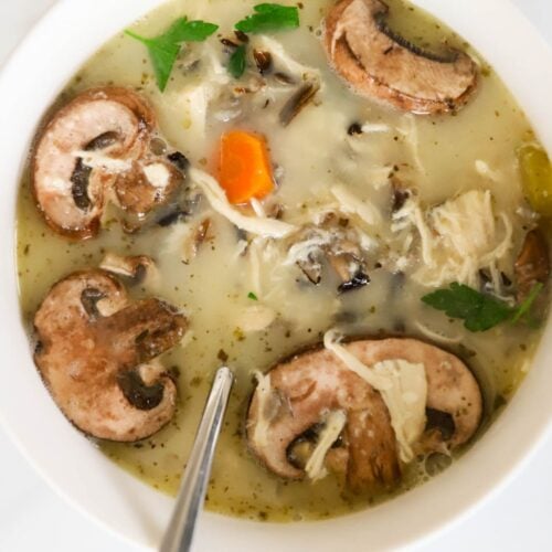 wild rice and chicken soup in a white bowl with a spoon.