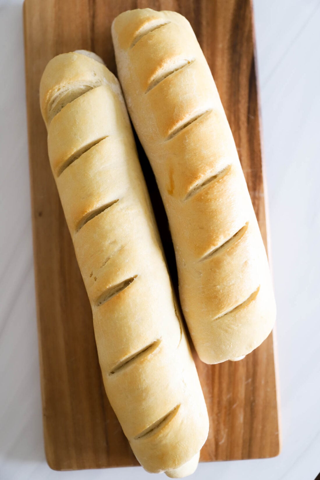 Two loaves of French bread on a wooden cutting board.