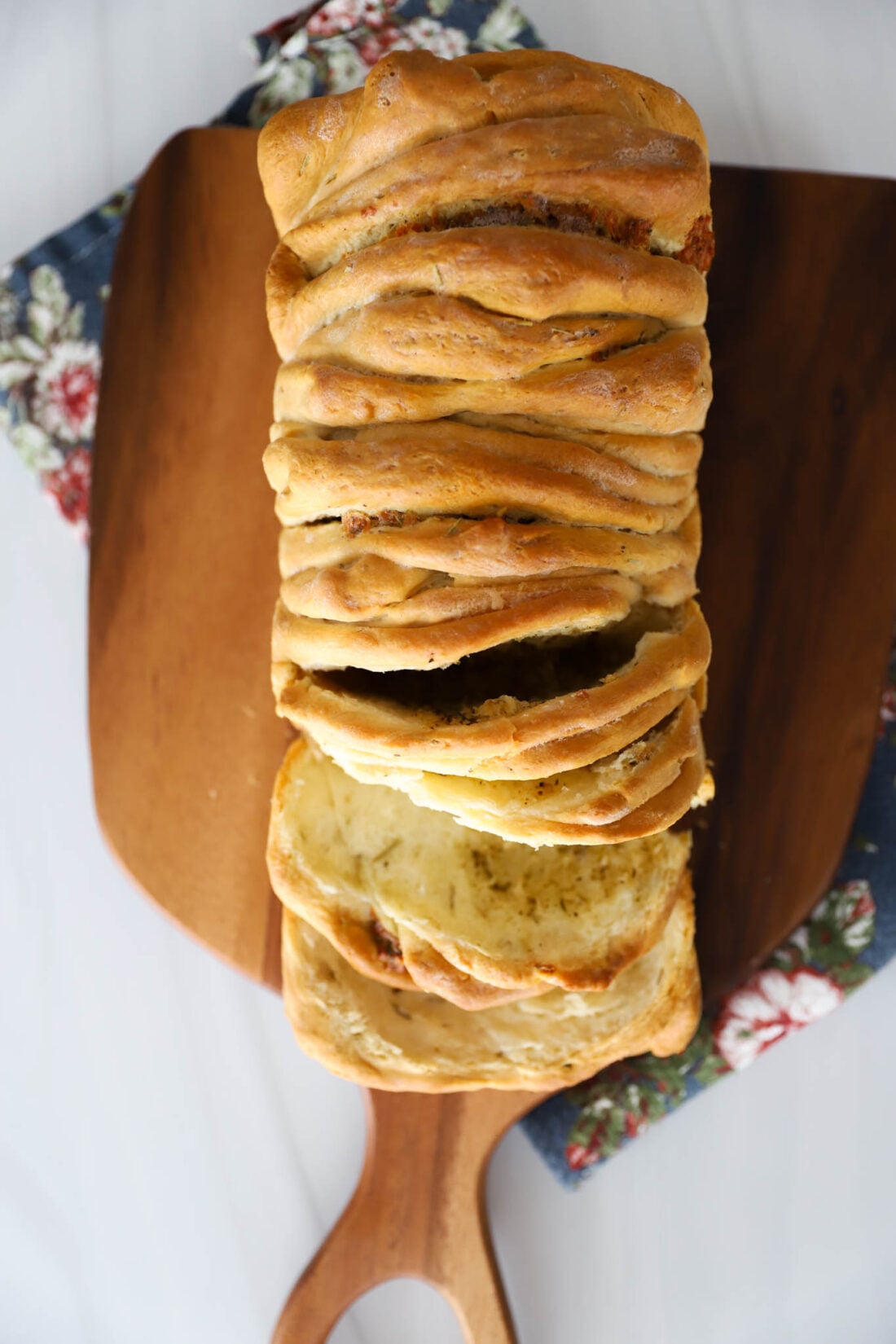 Rosemary pull apart bread on a cutting board.