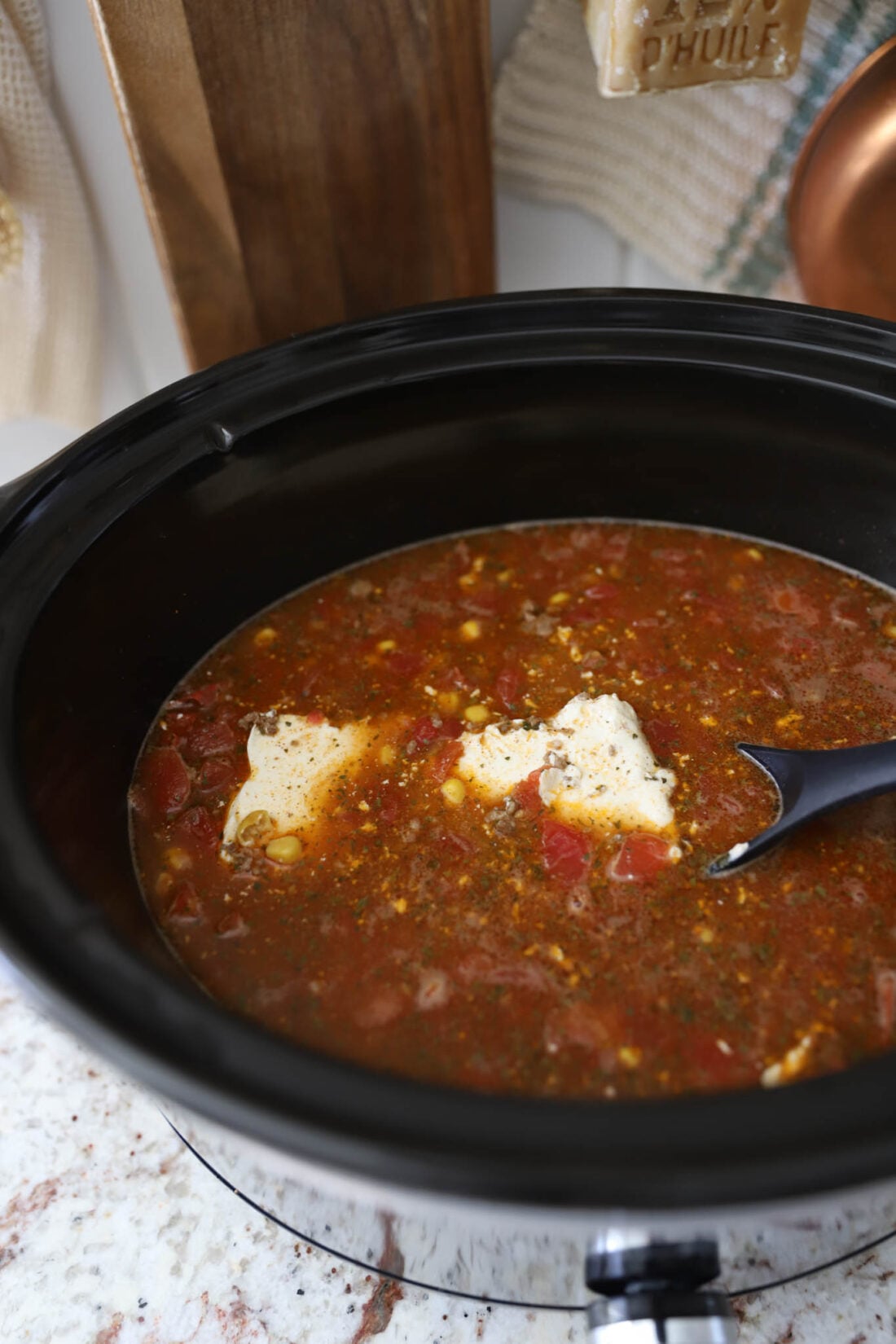 Delicious creamy taco soup made in a crockpot and in a white bowl with chips and sour cream.
